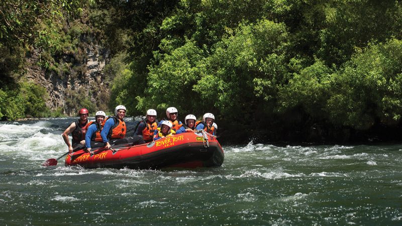 a group of people riding on the back of a boat in the water